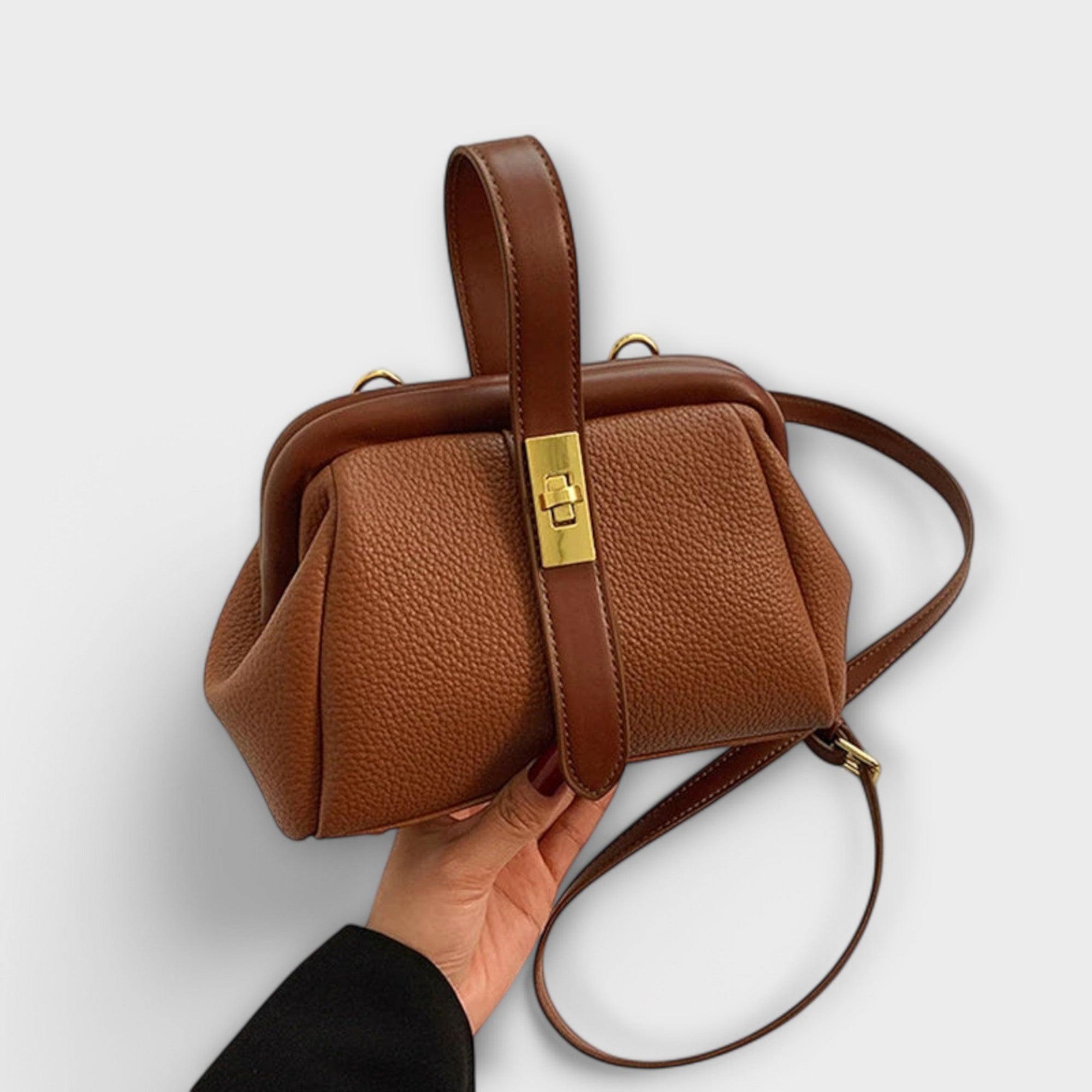 Sac rétro en cuir marron à poignée et bandoulière, fermoir doré rectangulaire.