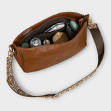Sac bandoulière vegan marron ouvert, intérieur avec poches et effets personnels visibles.