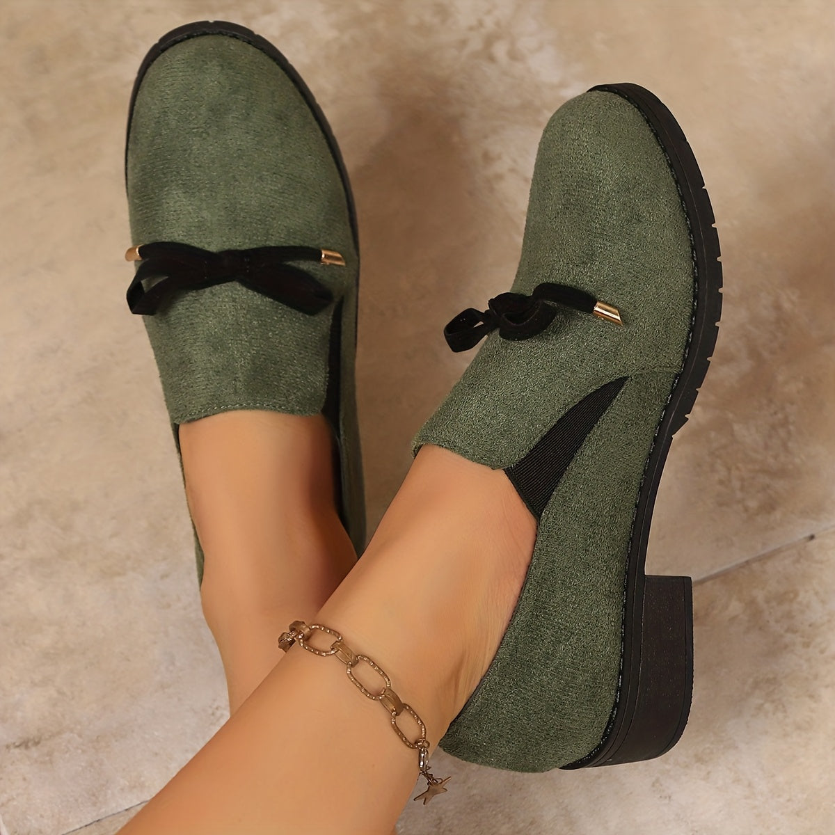 Mocassins verts à talon bloc, vue de profil et nœud noir sur l’empeigne.