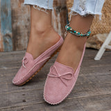 Sabots mocassin en daim rose poudré, motif perforé discret et nœud sur le bout.
