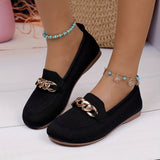 Chaussures plates noires texturées, avec chaîne dorée décorative sur l’avant.