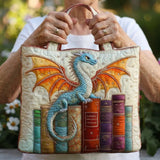 Sac matelassé crème aux broderies dragon bleu et livres colorés, tenu par les anses