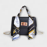 Sac à main noir avec foulard imprimé, rabat et fermoir rectangulaire, chaîne dorée.