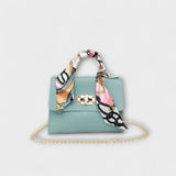 Sac à main bleu clair avec foulard imprimé, rabat et fermoir rectangulaire, chaîne dorée.